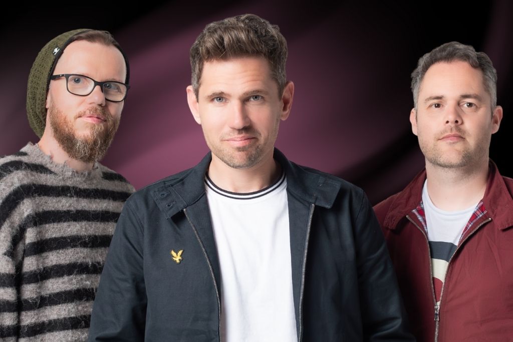 members of the band Scouting for Girls, standing against a dark, magenta background